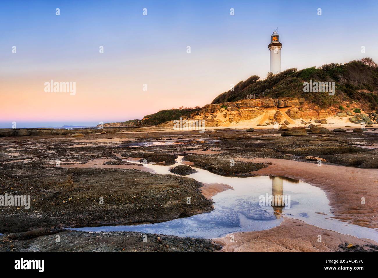 Meeresgrund bei Ebbe verlassen Salz Wasser Pfütze weißen Leuchtturm und rosa Himmel bei Sonnenaufgang auf australischen Pazifikküste zu reflektieren - Norah Landspitze, die Cen Stockfoto