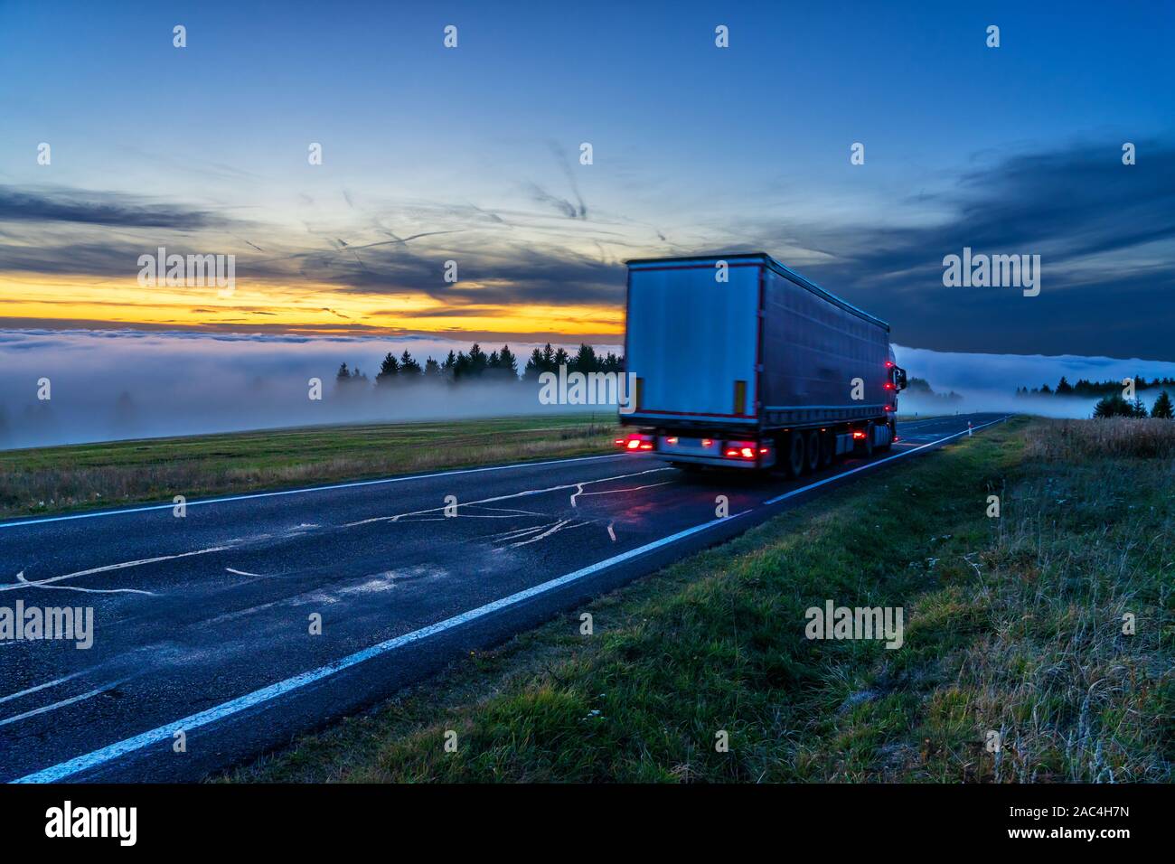 Stapler in den dichten Nebel von inversen Cloud auf der Asphaltstraße in Berglandschaft nach Sonnenuntergang Stockfoto