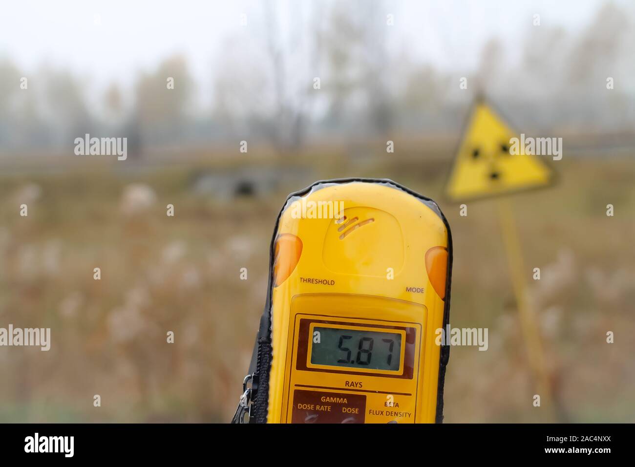 Ein Dosimeter ist vor der Radioaktivität Warnschild gehalten, 5,87 Millisievert pro. Stadt Pripyat, Sperrzone von Tschernobyl, Ukraine. Stockfoto