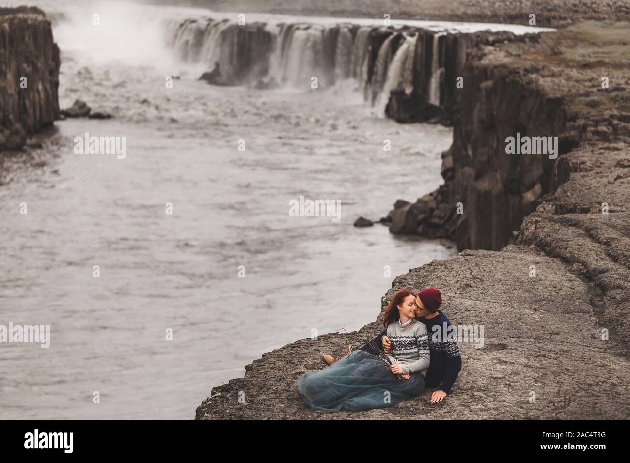 Happy hipster verliebtes Paar in Island. Traditionelle wolle Pullover, rote Haare, Grauer Rock. Berühmten Wasserfall Selfoss auf Hintergrund, dramatische nordischen Landschaft. Stockfoto