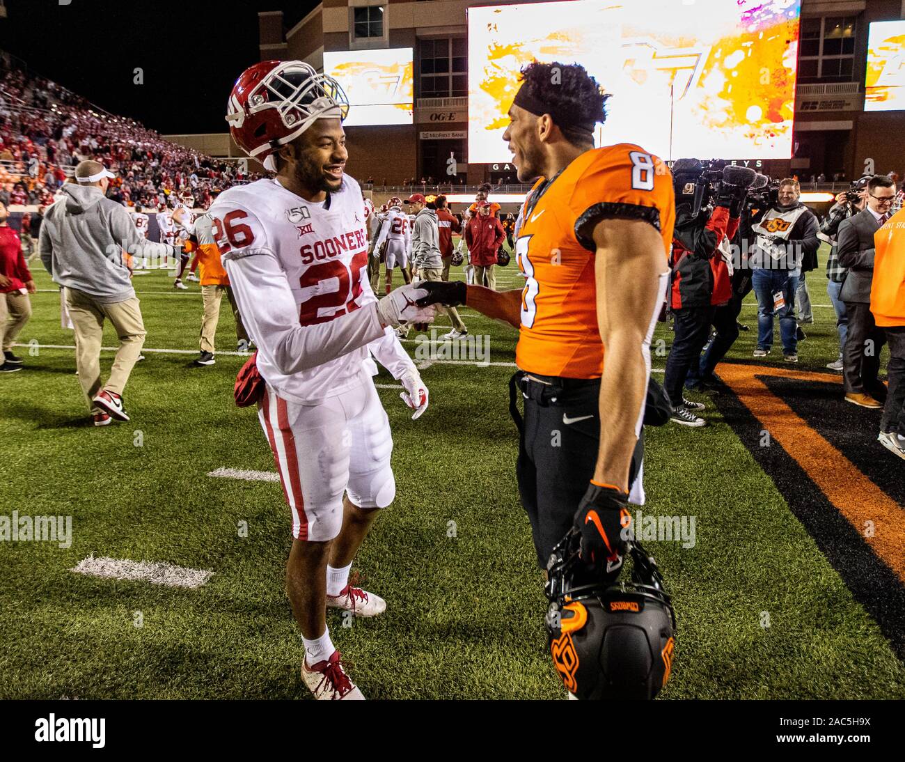 Stillwater, Oklahoma, USA. 30 Nov, 2019. Oklahoma Sooners zurück laufen Kennedy Brooks (26) und der Oklahoma State Cowboys cornerback Rodarius Williams (8) Hände schütteln Nach ihrem Spiel am Samstag, den 30. November 2019 an der Boone Pickens Stadion in Stillwater, Oklahoma. Credit: Nicholas Rutledge/ZUMA Draht/Alamy leben Nachrichten Stockfoto