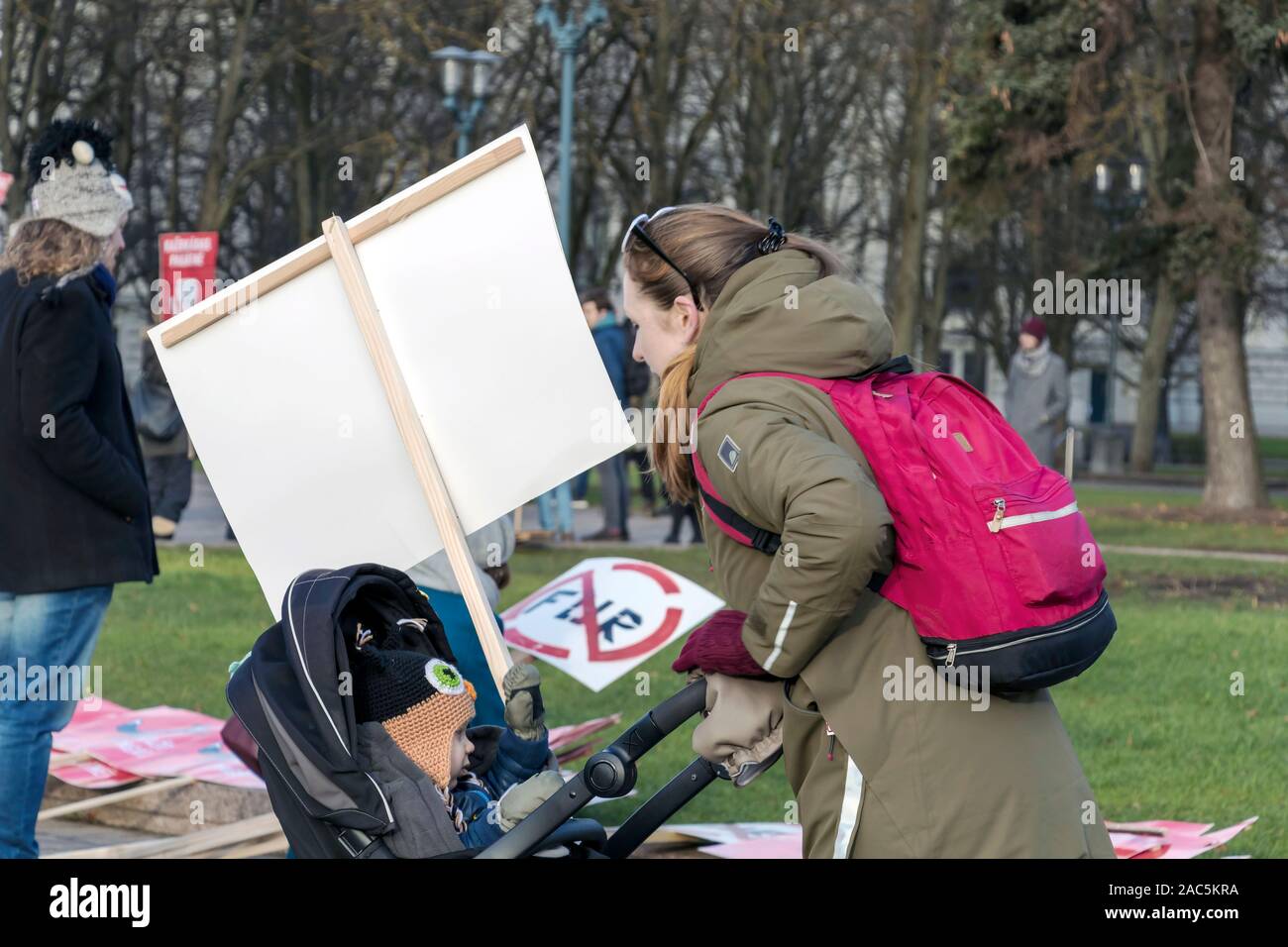 Riga, Lettland - 30. November 2019: Junge Mutter mit ihrem Kind im Kinderwagen und keinen Pelz schild Plakat im März für Tierschutz in Riga, Lettland, Stockfoto