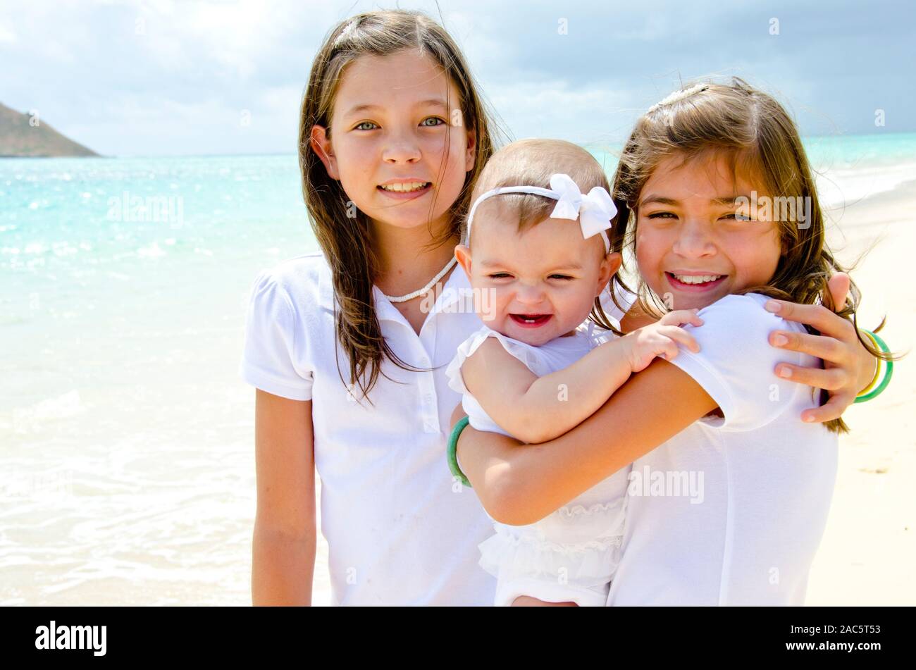 Schwestern Leilani und Ke'alohi kümmert sich um Ihre kleine Schwester Emma am Strand Stockfoto