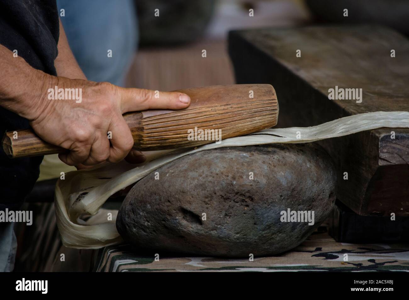 Kapa auf der Big Island: Erste Schlagen des wauke (Maulbeerbaum) Bast mit einem hohoa (runde Holzhammer, wendetrommel) auf einem kua pohaku (Stein Amboss); Stockfoto