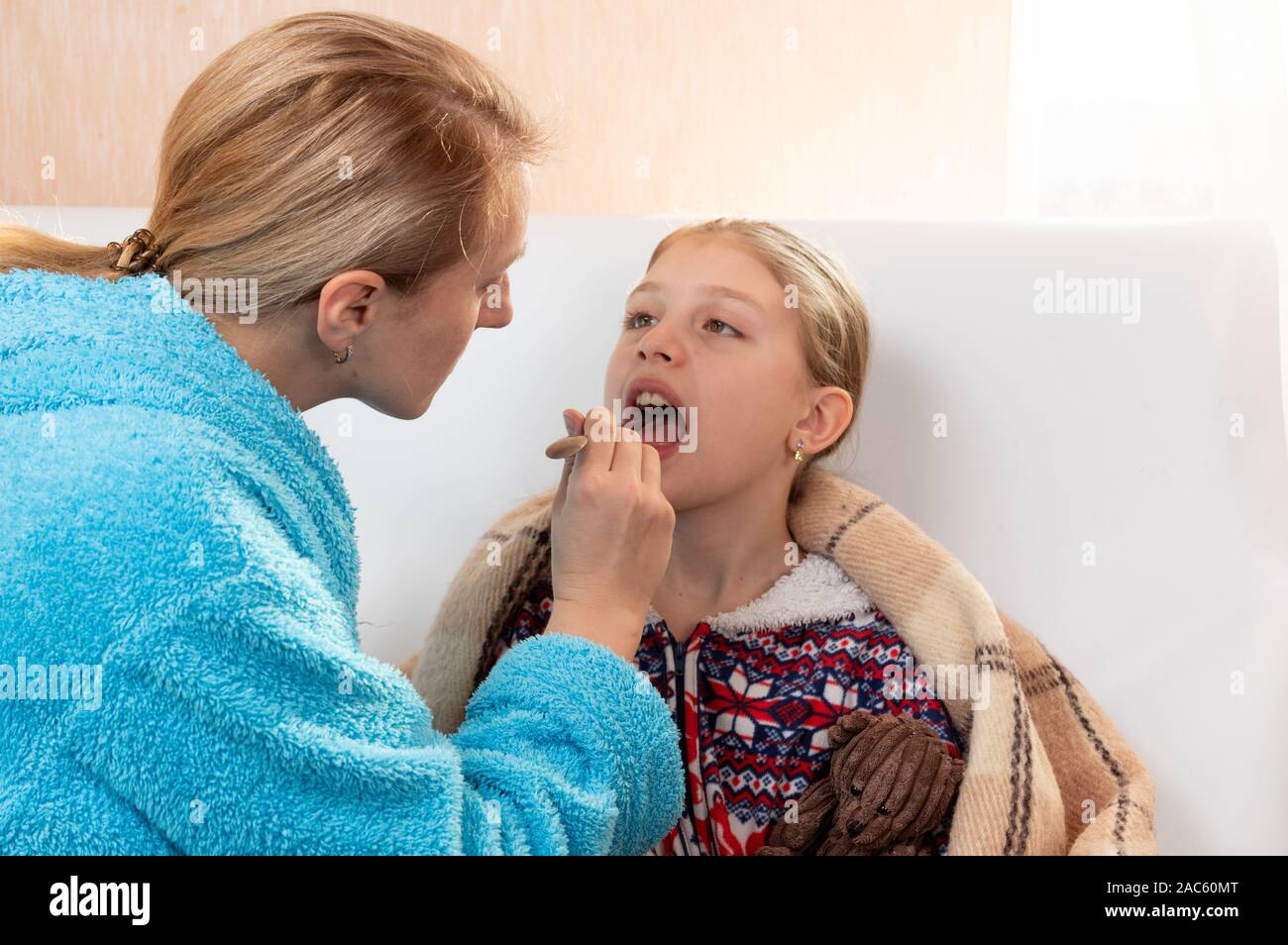 Ein Arzt prüft die Kehle eines Patienten. Hals behandeln. Das Mädchen öffnete ihren Mund zu prüfen. Stockfoto