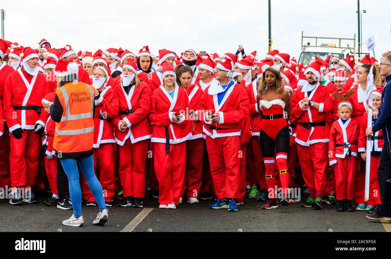 Mit einer Menschenmenge konfrontiert, die sich alle als Weihnachtsmann verkleidet haben und auf den Betrachter für die jährliche Wohltätigkeitsveranstaltung "Santa's on the Run" Pilgrims Hospices warten. Herne Bay, Kent, England. Stockfoto