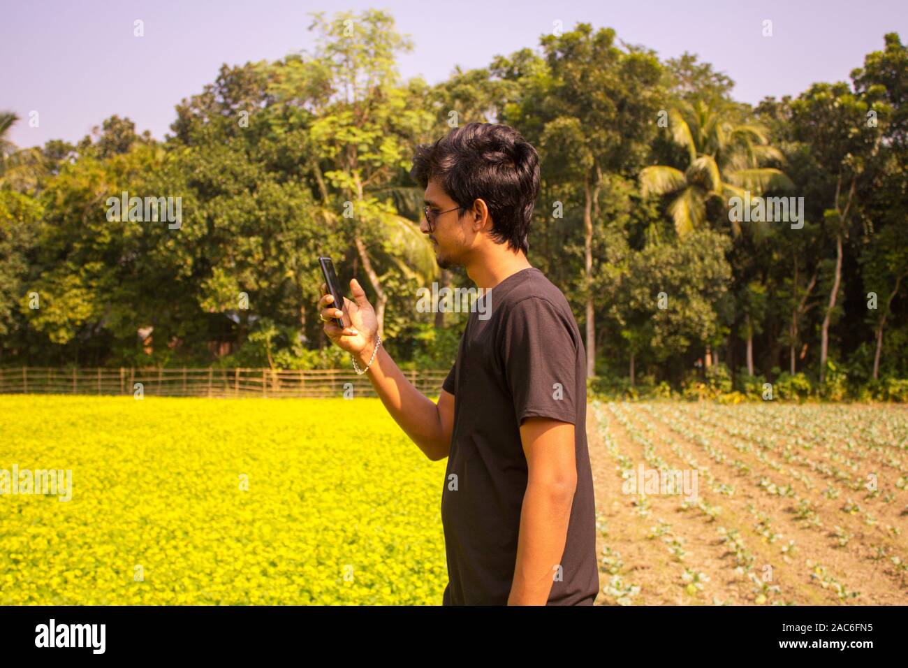 Ein Junge mit seinem Handy Posing, mobile Netz im Dorf suchen, Hintergrund ist die Natur. Stockfoto