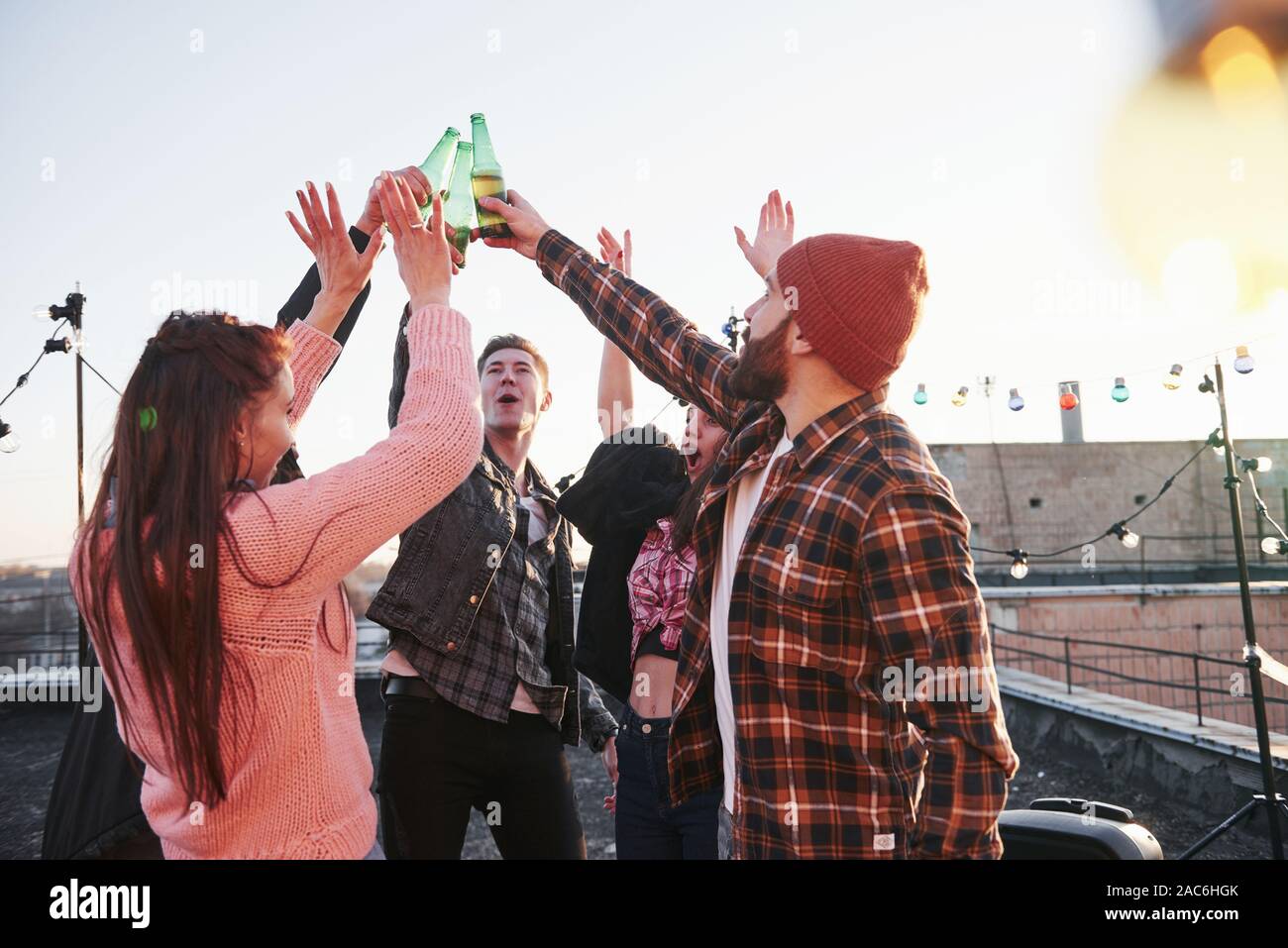Urlaub auf dem Dach. Fröhliche Gruppe von Freunden hoben ihre Hände mit Alkohol Stockfoto