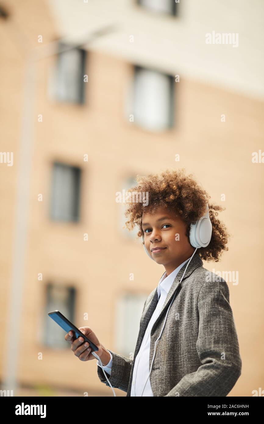 Portrait der Afrikanischen Schüler in Kopfhörer holding Handy und Kamera beim Stehen im Freien Stockfoto
