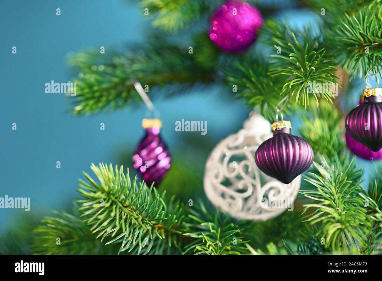 In der Nähe von schönen lila Glas baum Christbaumkugel mit geschmückten Weihnachtsbaum mit anderen saisonalen Baumschmuck auf blauem Hintergrund Stockfoto
