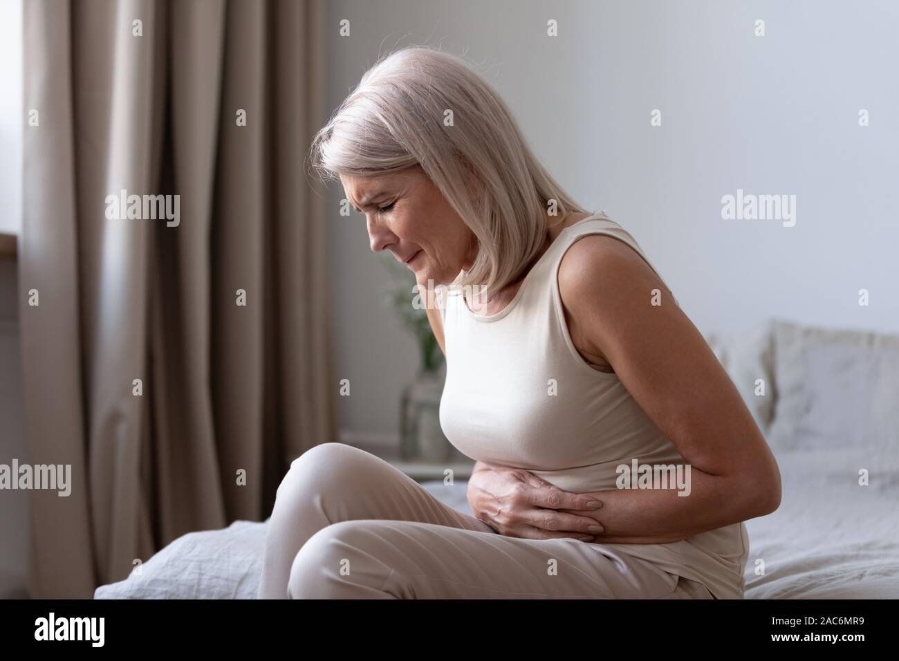 Alte ungesunde Frau leidet an schweren Kopfschmerzen Bauchschmerzen Stockfoto