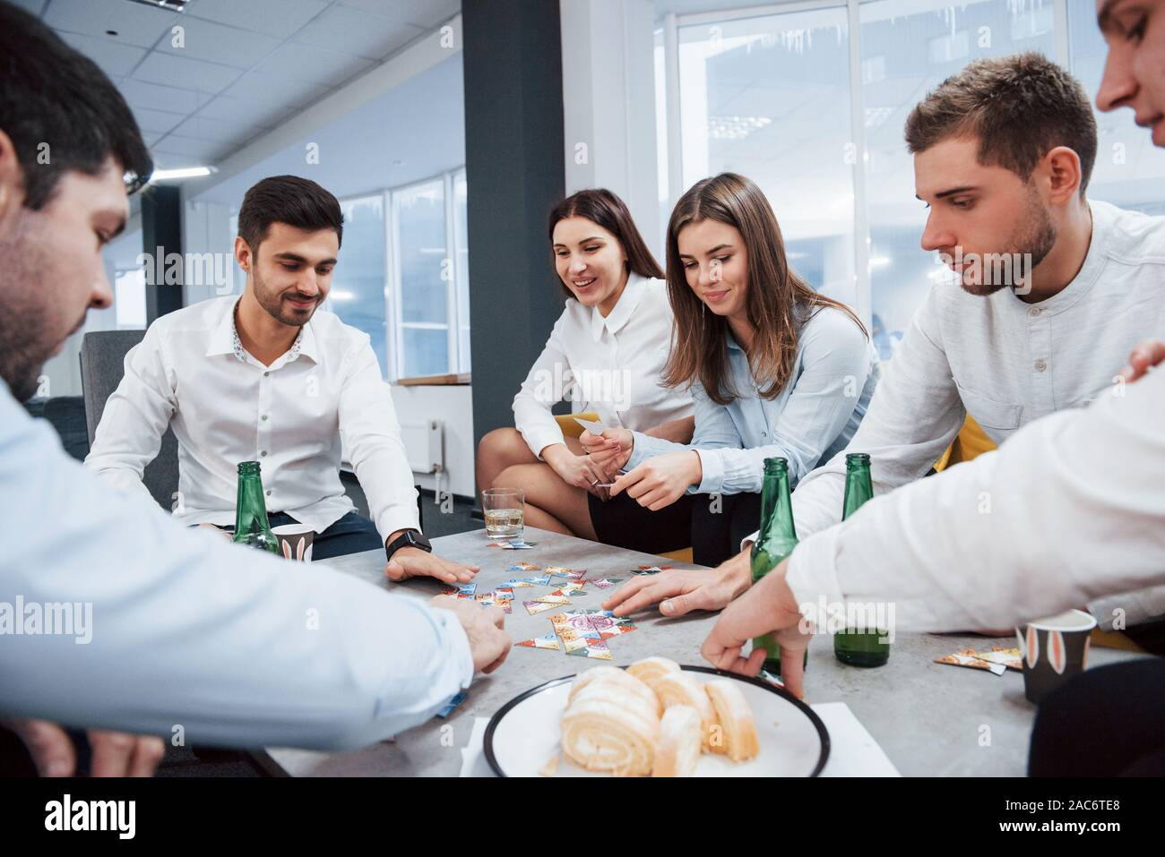 Mit einem Rest nach einem harten Tag. Entspannen mit Spiel. Feiern erfolgreichen Abschluss. Junge Berufstätige sitzt in der Nähe des Tisches mit Alkohol Stockfoto