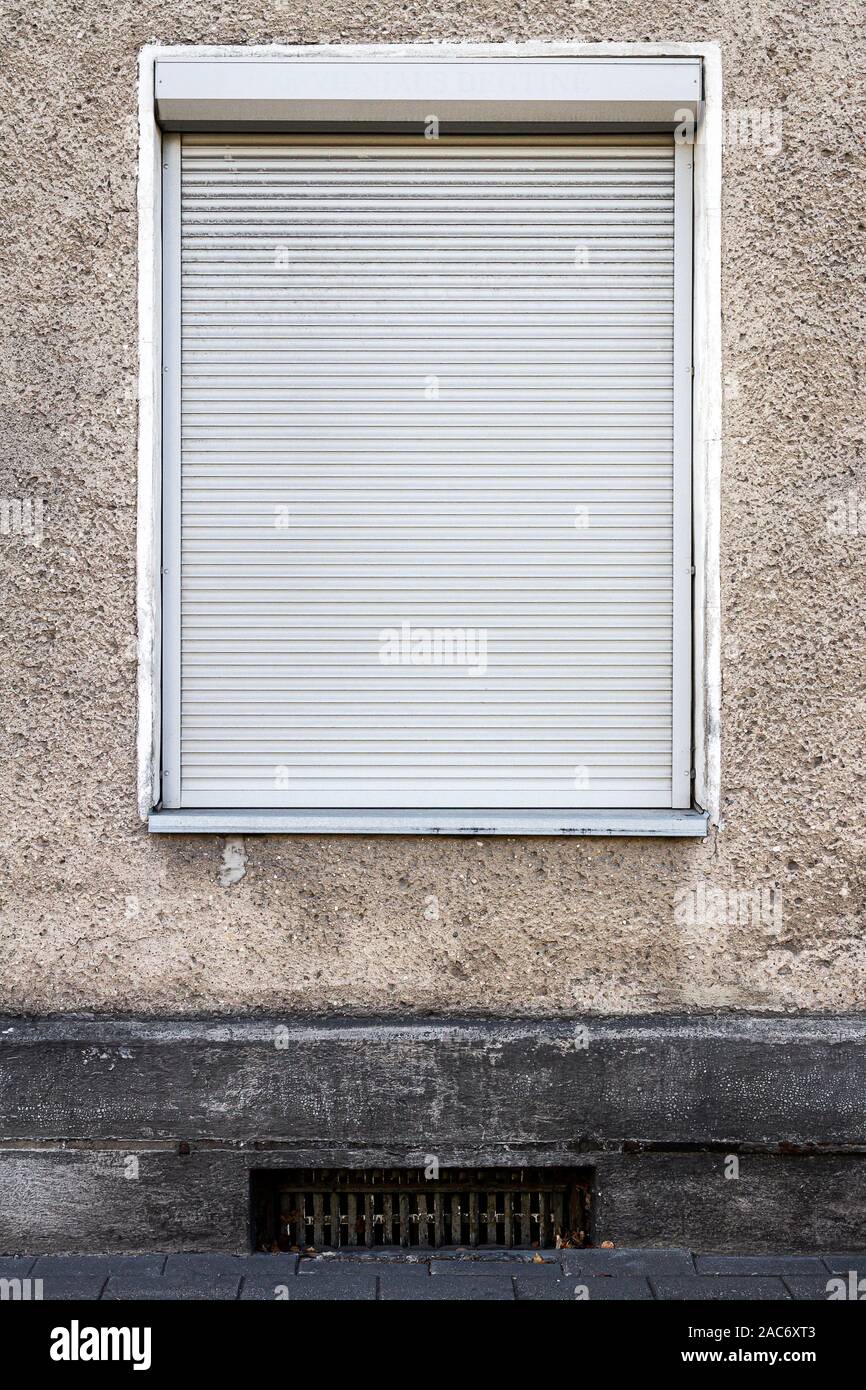 Alte graue Wand mit einem Fenster mit Jalousien Stockfoto