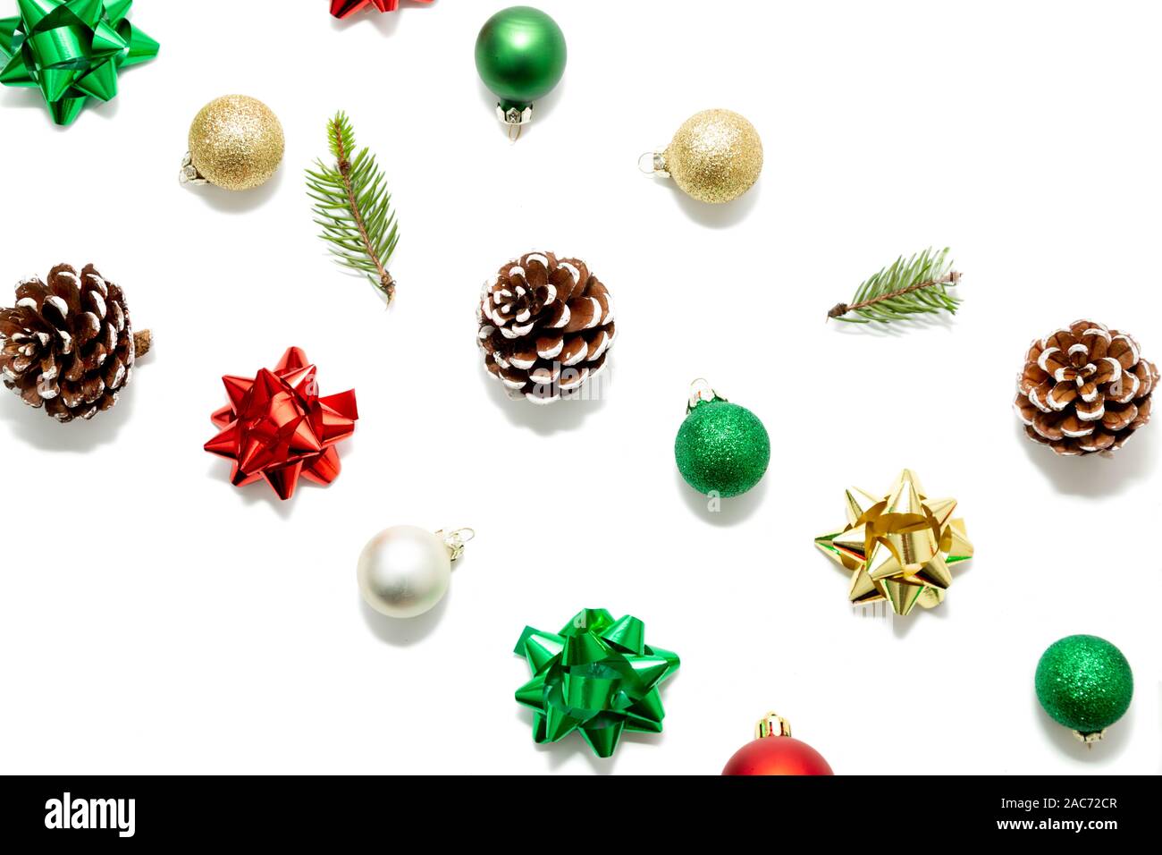 Weihnachten diagonale Komposition mit roten, grünen und goldenen Kugeln, Schleifen, Tannenzweigen und Tannenzapfen isoliert auf weißem Stockfoto