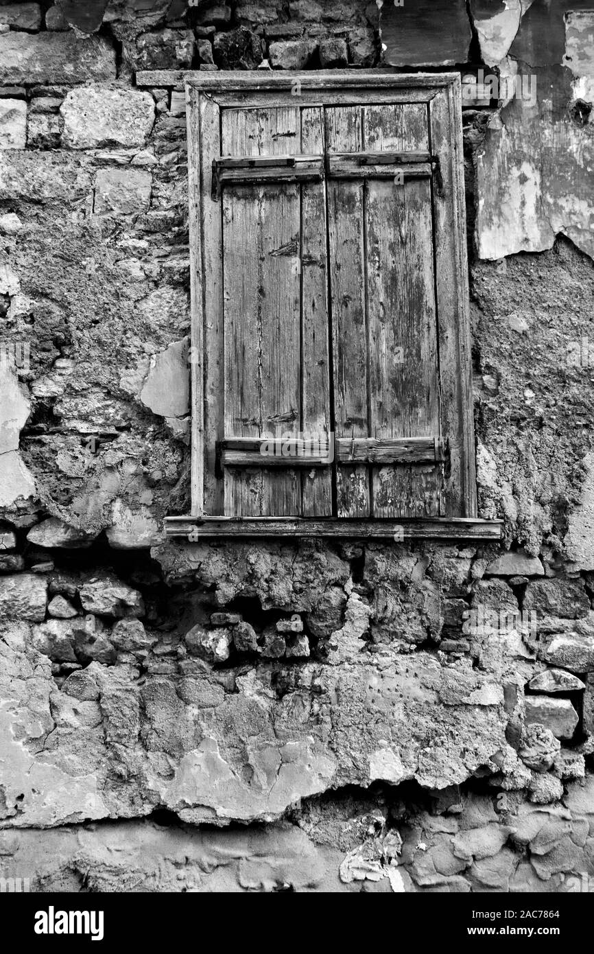 Texturierte Wand der alten heruntergekommenen Haus mit Fenster mit Fensterläden geschlossen. Schwarze und weiße architektonisches Detail Stockfoto