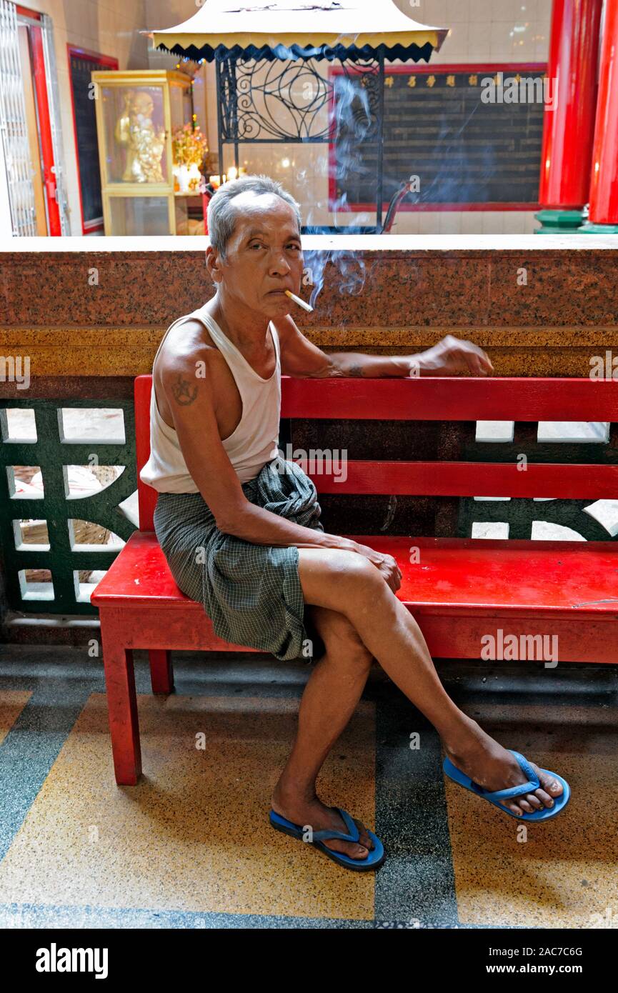 Mann Rauchen einer Zigarette in der Chinatown von Yangon, Myanmar Stockfoto