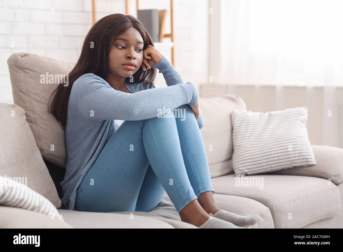Lonely afrikanische amerikanische Frau auf der Couch zu Hause sitzen betätigt Stockfoto
