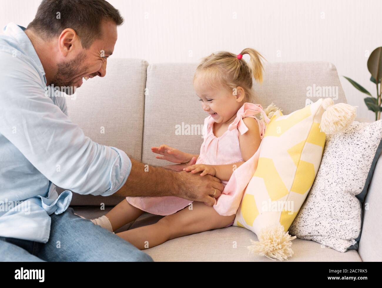 Happy dad Kitzeln sein kleines Mädchen auf der Couch Stockfoto