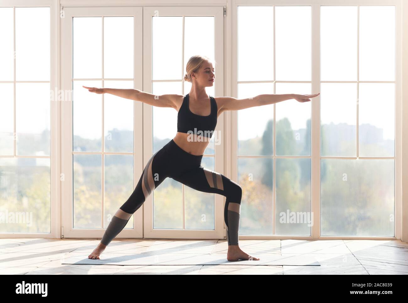 Aktive junge Frau, die Warrior yoga Pose im Studio Stockfoto