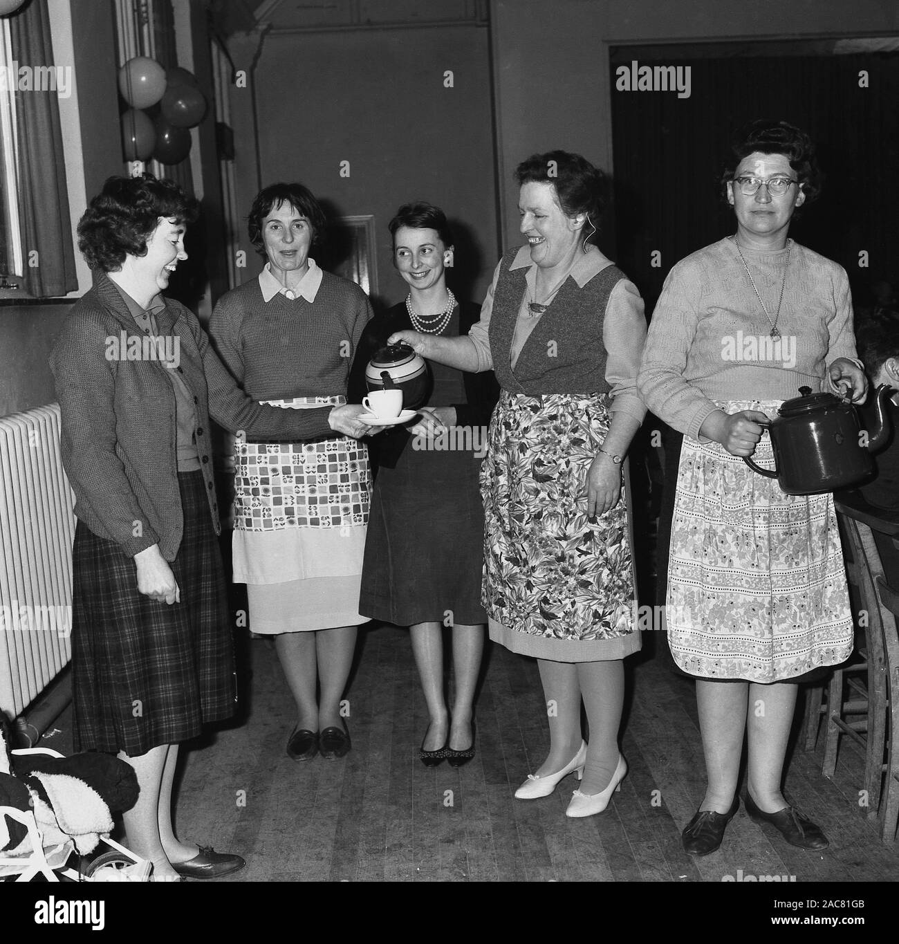 1960, historische, zwei Damen in Schürzen gießen Tee für Ihre weiblichen Gäste an einer Partei, England, UK. Stockfoto