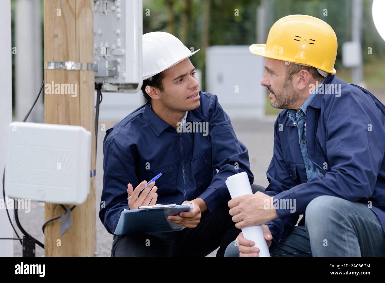 Zwei männliche Techniker in der Diskussion beim Lesen im Freien m Stockfoto