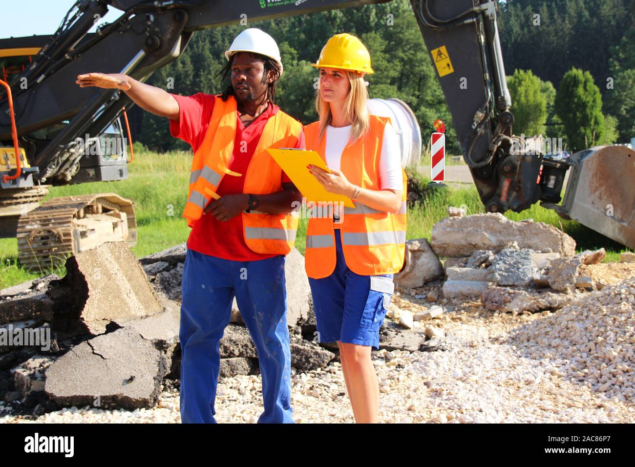 Männliche und weibliche Bauarbeiter Analyse der Pläne auf der Baustelle Stockfoto