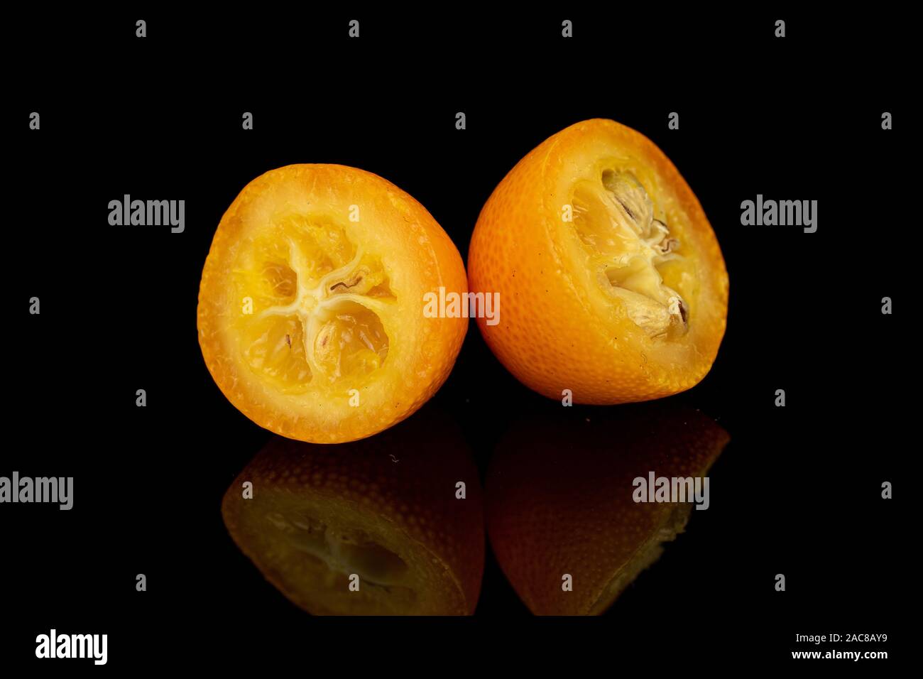 Gruppe von zwei Hälften der leckere Orange kumquat auf schwarzem Glas isoliert Stockfoto