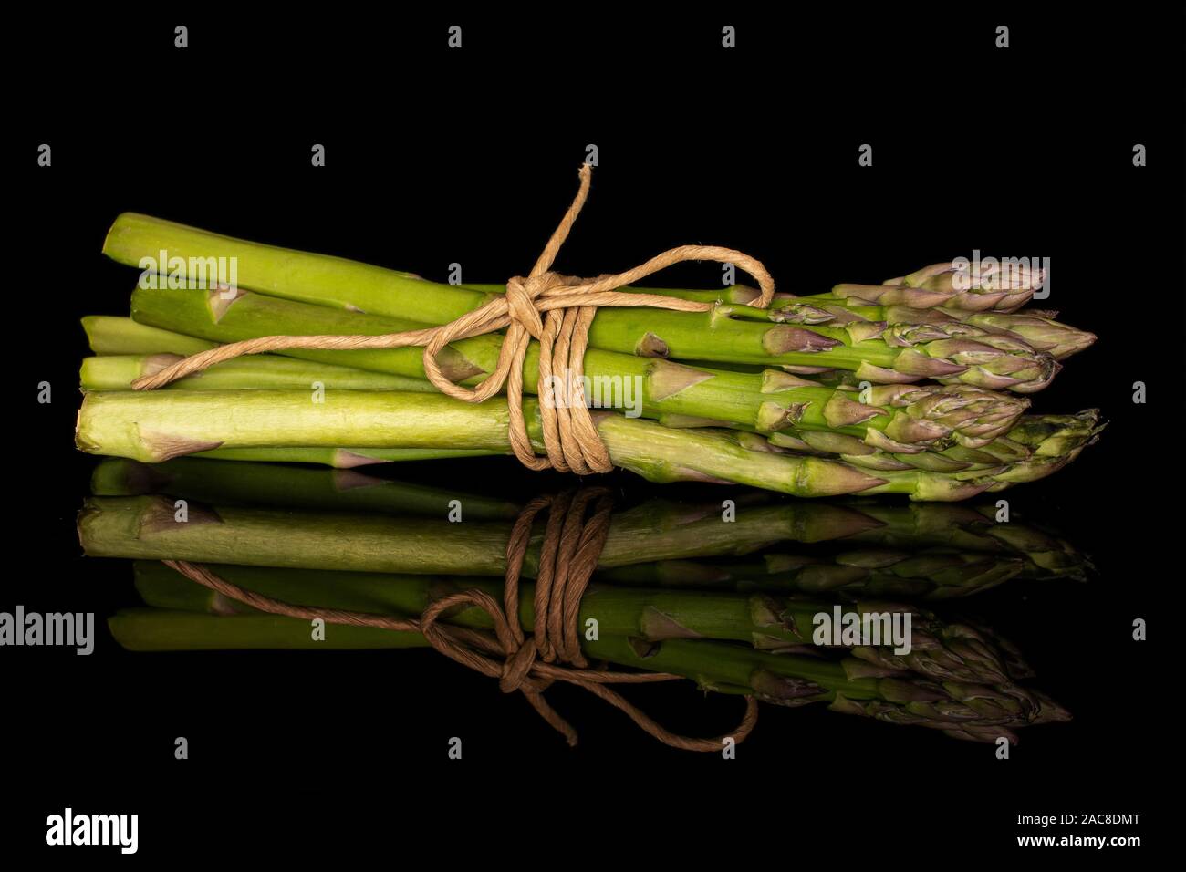 Menge ganz gesunden grünen Spargel mit Stroh Seil auf schwarzem Glas isoliert Stockfoto