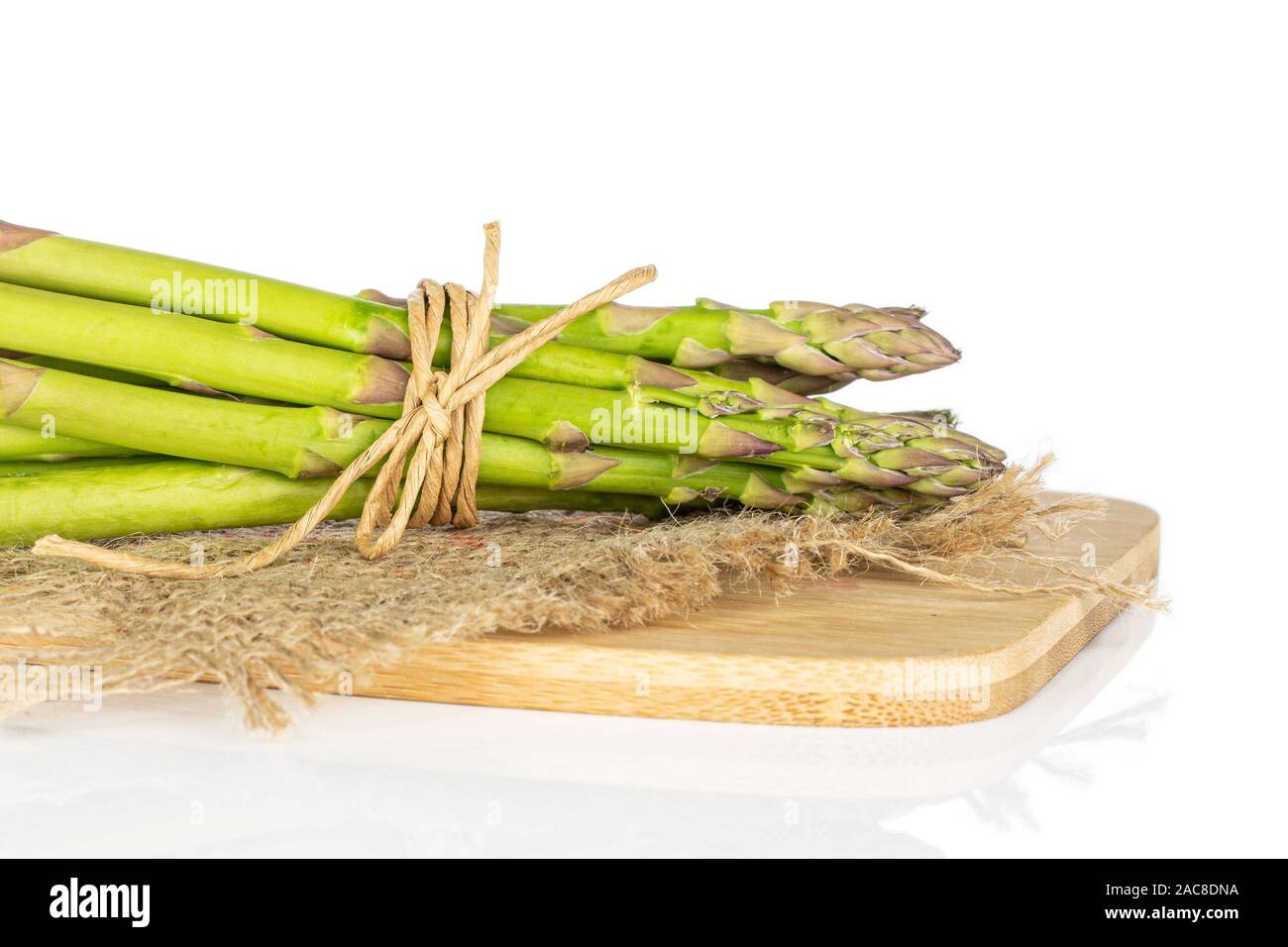 Menge ganz gesunden grünen Spargel auf Bambus Schneidebrett mit Stroh Seil und Jutegewebe auf weißem Hintergrund Stockfoto