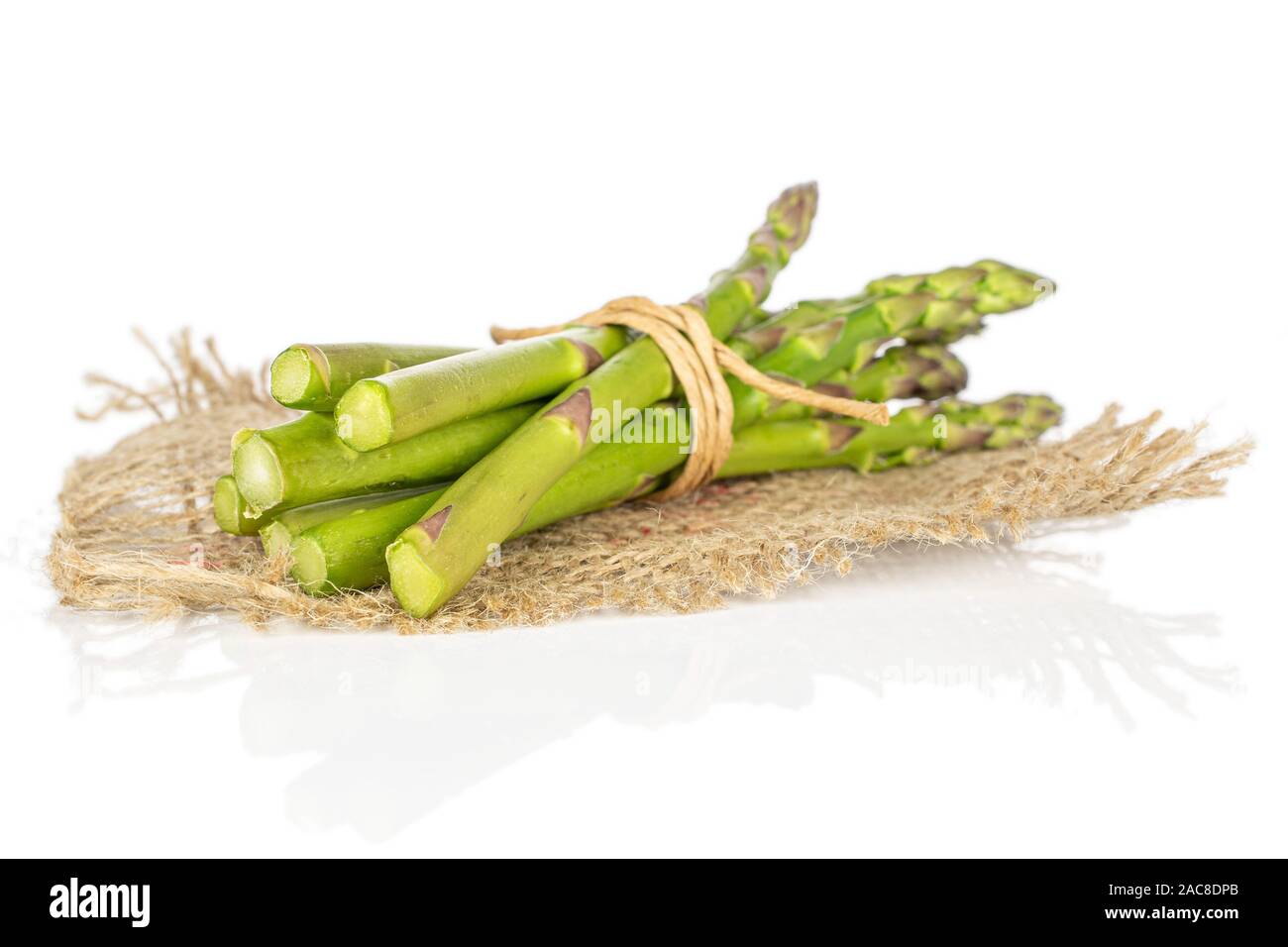 Menge ganz gesunden grünen Spargel mit Stroh Seil und Jutegewebe auf weißem Hintergrund Stockfoto