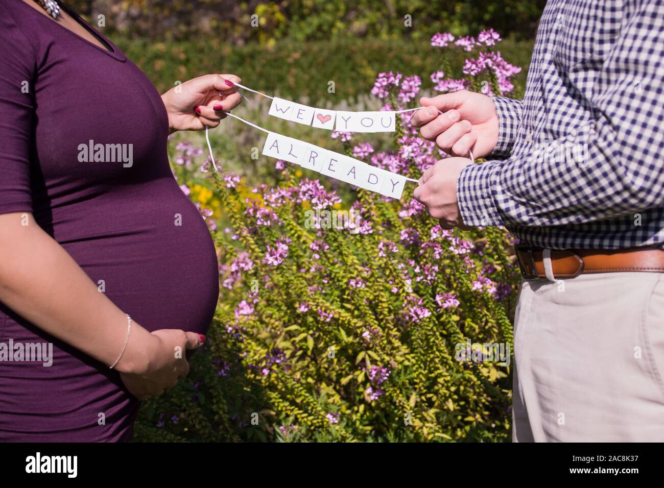 Eine schwangere Paar erhält bereit, eine Familie in einem matnerity Fotoshooting, wo Sie ein nettes Zeichen für das Baby halten zu werden Stockfoto