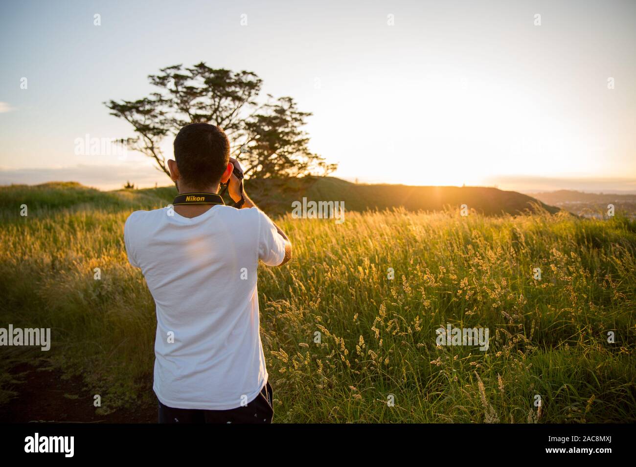 Menschen fotografieren mit einer Nikon Kamera während der wunderschöne Goldene Stunde Sonnenuntergang am Gipfel des Mount Wellington in Auckland, Neuseeland Stockfoto