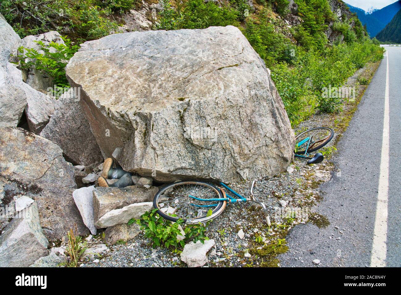 Fahrräder und Stiefel unter großen Felsen auf der Seite der Straße gelegt, als ob sie durch Steinschlag in der Nähe von Hyder Alaska zerquetscht wurden. Stockfoto