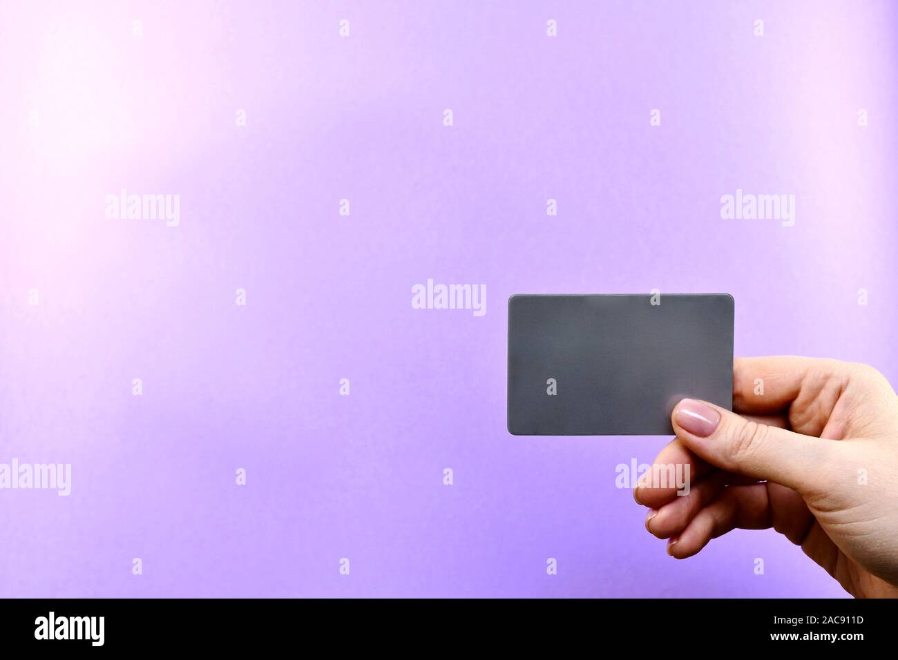 Demonstration einer grauen Karte in eine Hand auf einem violetten Hintergrund. Stockfoto