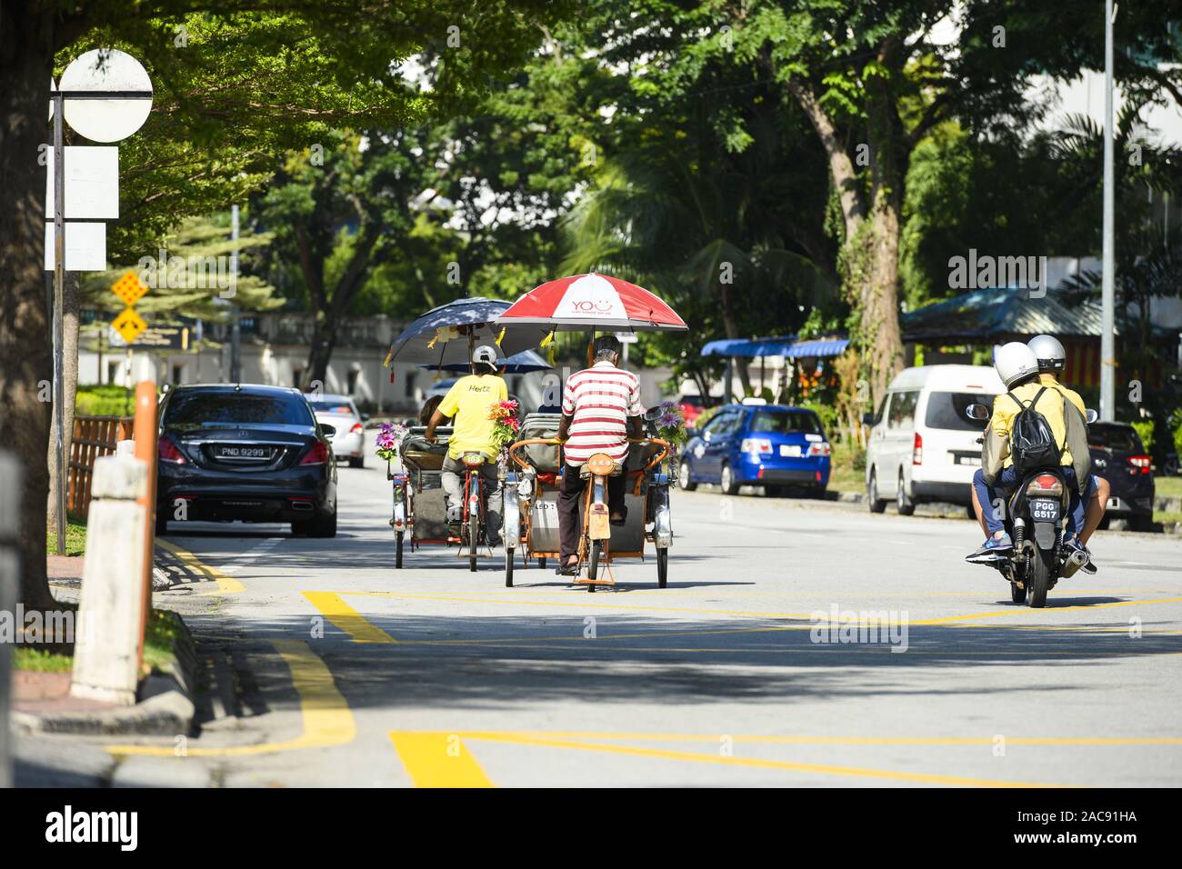 Einige Trishaw Fahrer fahren durch die Straßen von George Town. George Town ist die Hauptstadt der P Stockfoto