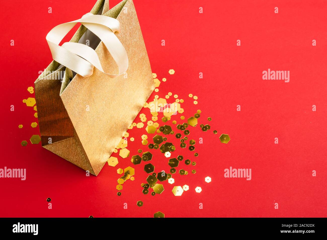 Gold Papier Shopping Bag und trendigen sechseckige funkelt auf rotem Hintergrund. Urlaub verkauf Konzept, isometrische Ansicht. Stockfoto