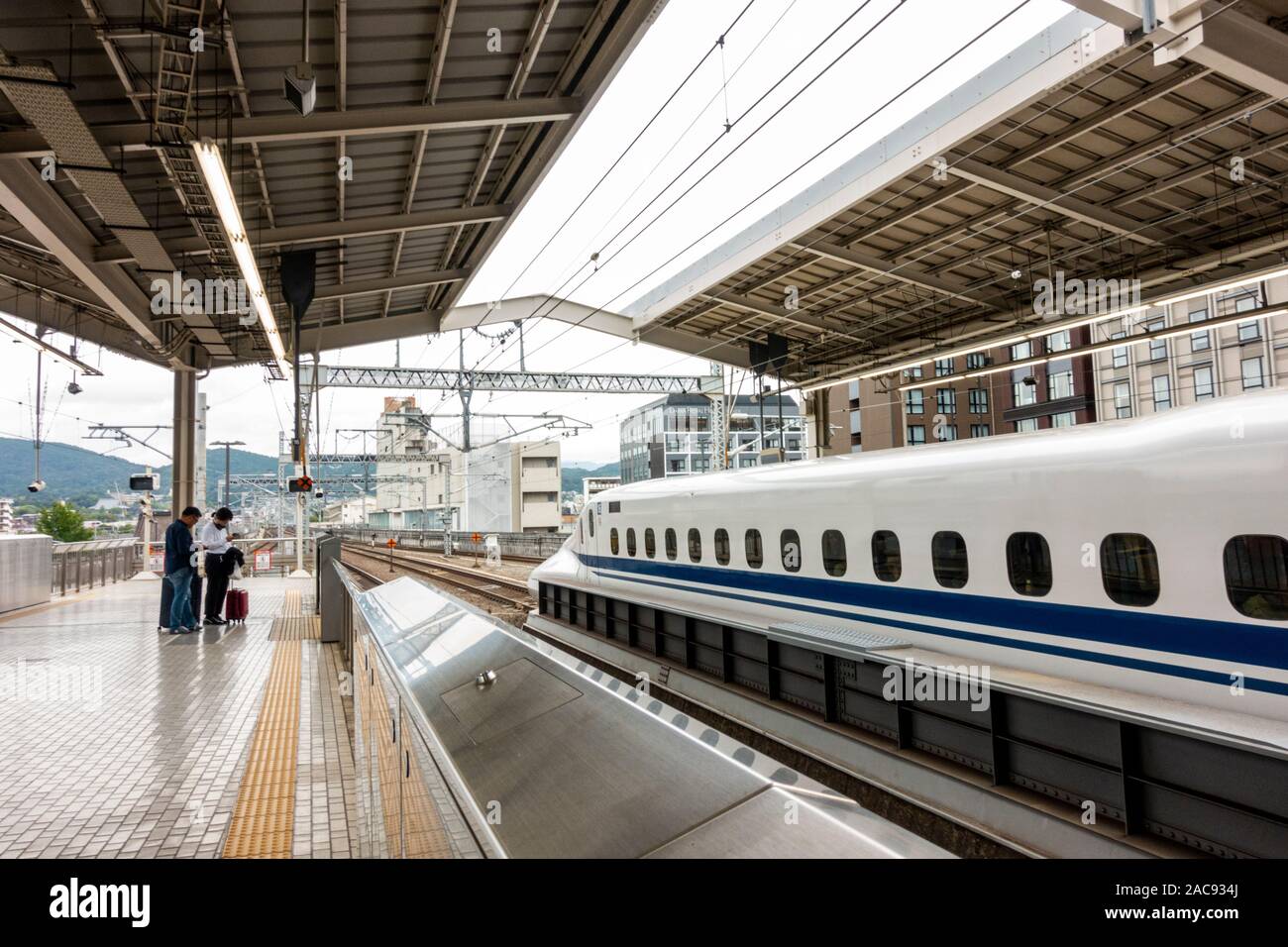 Oder japanischen Hochgeschwindigkeitszug Shinkansen von Osaka Station mit Passagiere mit Gepäck warten auf der Plattform in der Telefone suchen Stockfoto