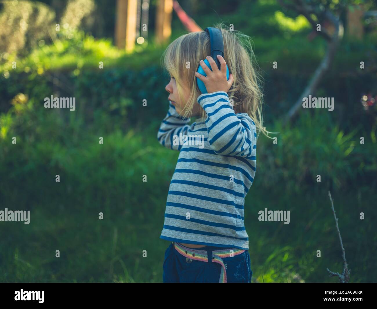 Ein kleines Kind ist das Tragen von Gehörschutz in einem Garten Stockfoto