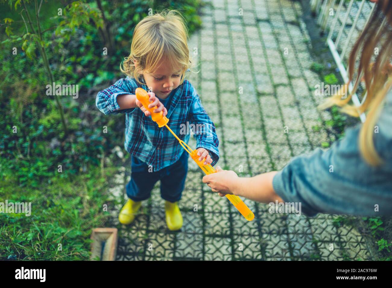 Ein kleines Kind Seifenblasen im Garten mit seiner Mutter Stockfoto