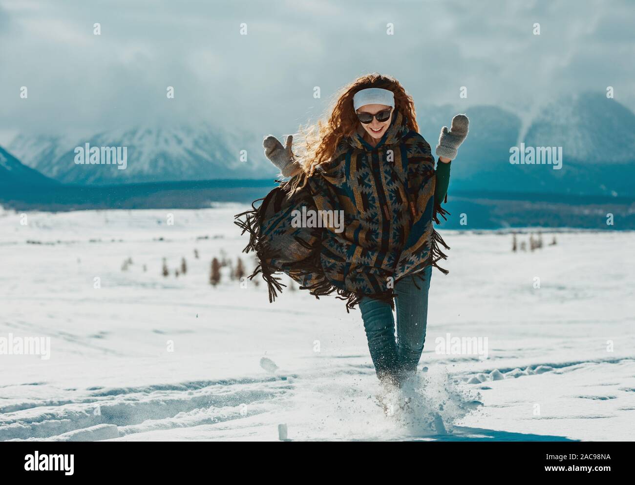 Junge glücklich in Poncho läuft im Pulverschnee in den Bergen Bereich gekleidet Stockfoto