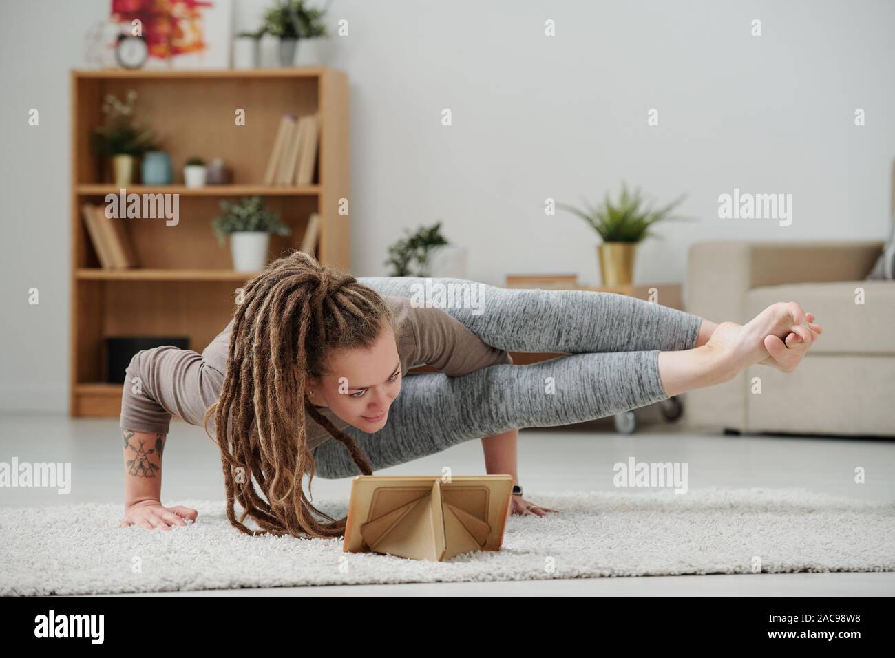 Junge Frauen stehen auf Händen in Yoga Positionen vor Touchpad Stockfoto