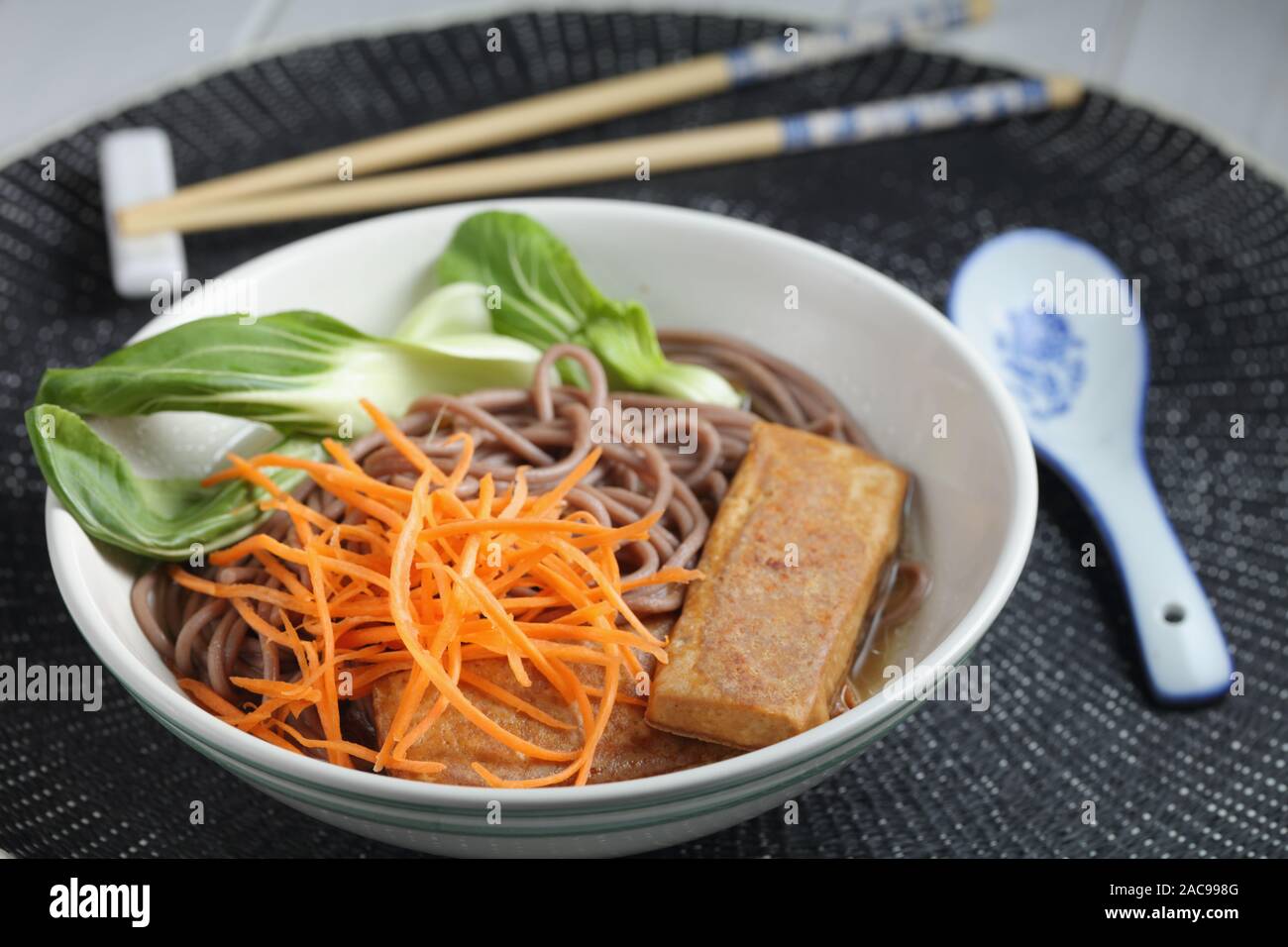 Teil der Soba Nudelsuppe mit Scheiben von gebratenem Tofu, Karotte, und Blätter von Bok Choy Stockfoto