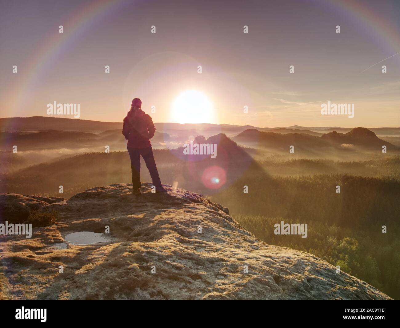 Frauen in morgen So. Wanderer Mädchen in starken Sonnenstrahlen mit vielen Schüben um ihren Körper. Morgen neblig Natur im Hintergrund Stockfoto