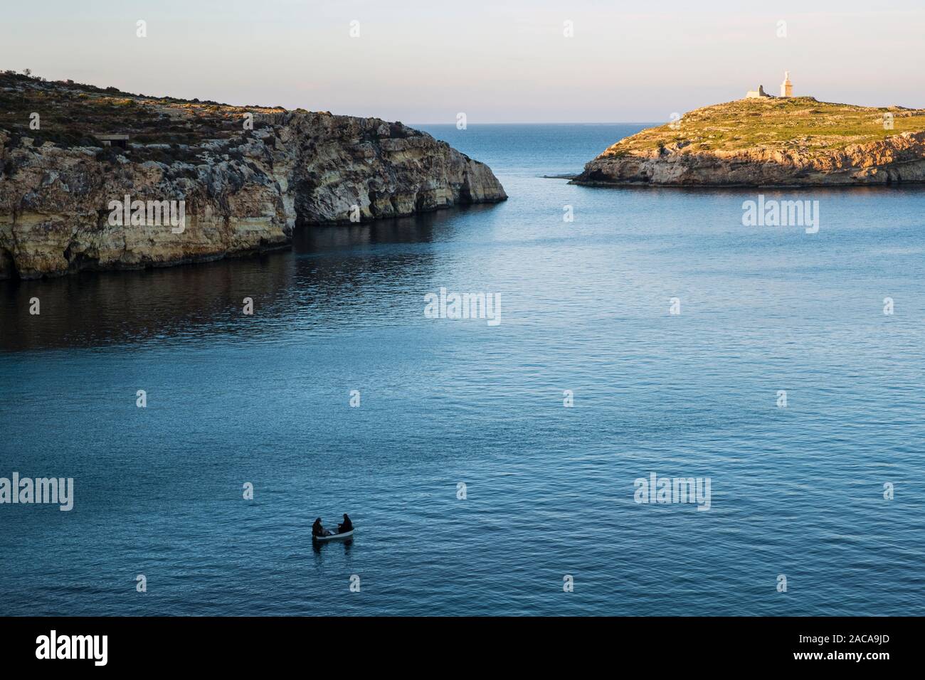 Abendlicher Blick in Richtung Selmunet oder Saint Paul's Islands und zwei Männer aus dem Boot, Malta Stockfoto