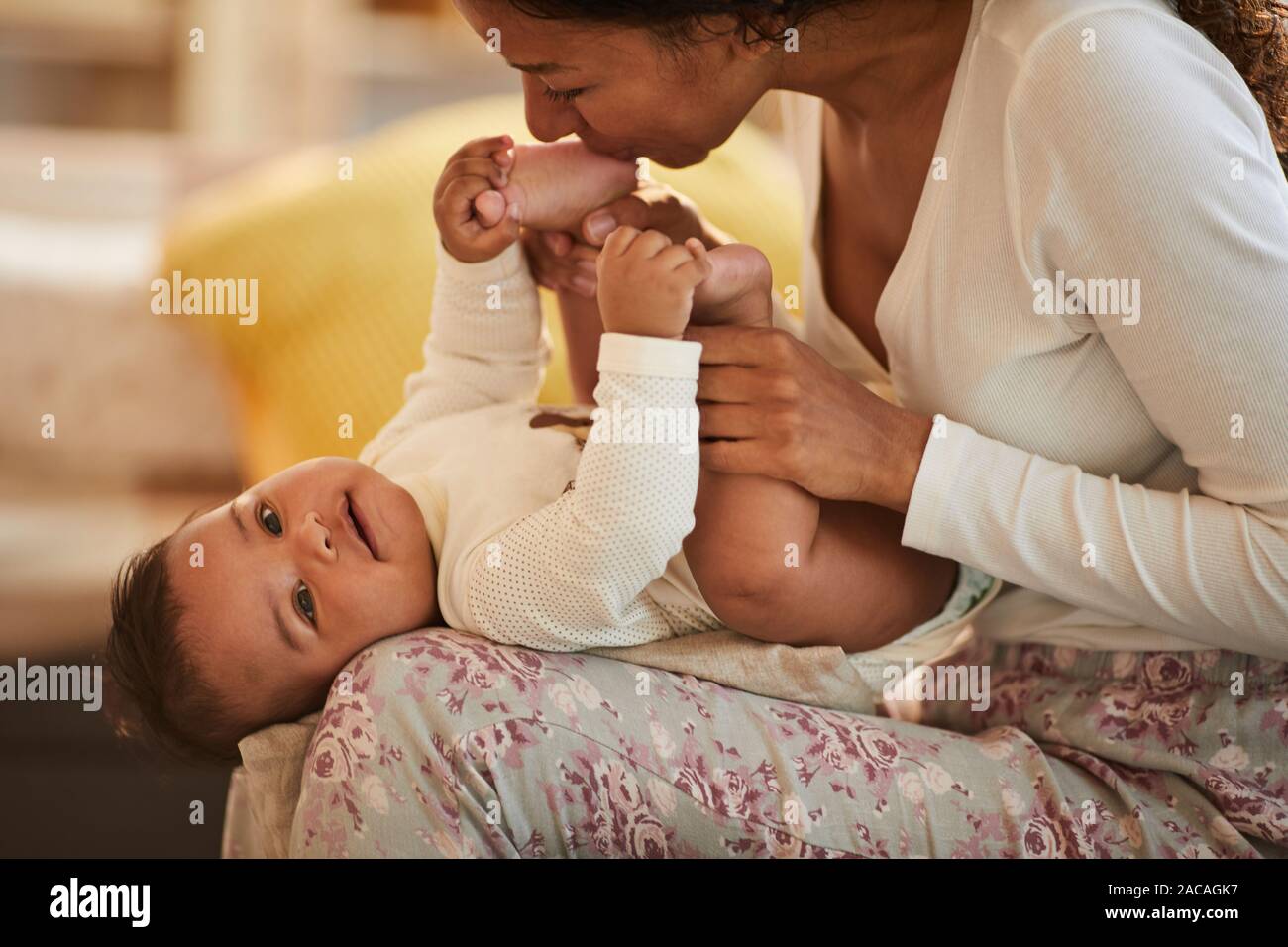 Portrait der Pflege Afro-amerikanische Mutter küssen Füße von niedlichen Baby Junge beim Kuscheln, Kopie Raum Stockfoto