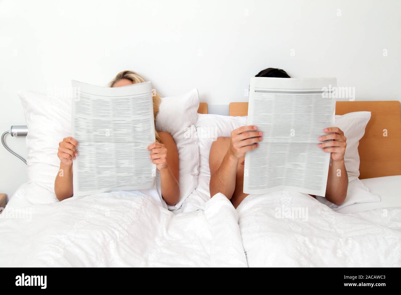 Paar im Bett und liest Zeitung. Informationen und Neuigkeiten Stockfoto