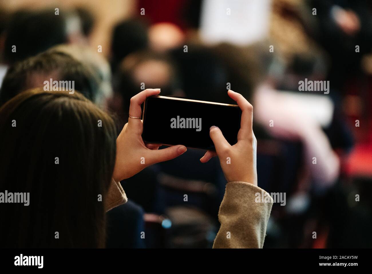 Eine Frau nimmt ein Bild mit einem Mobiltelefon in einem Meeting Stockfoto