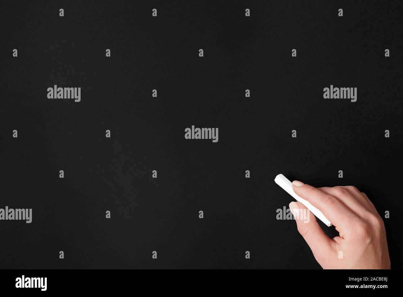 Hand mit Kreide gegen leere Schiefertafel Hintergrund Stockfoto