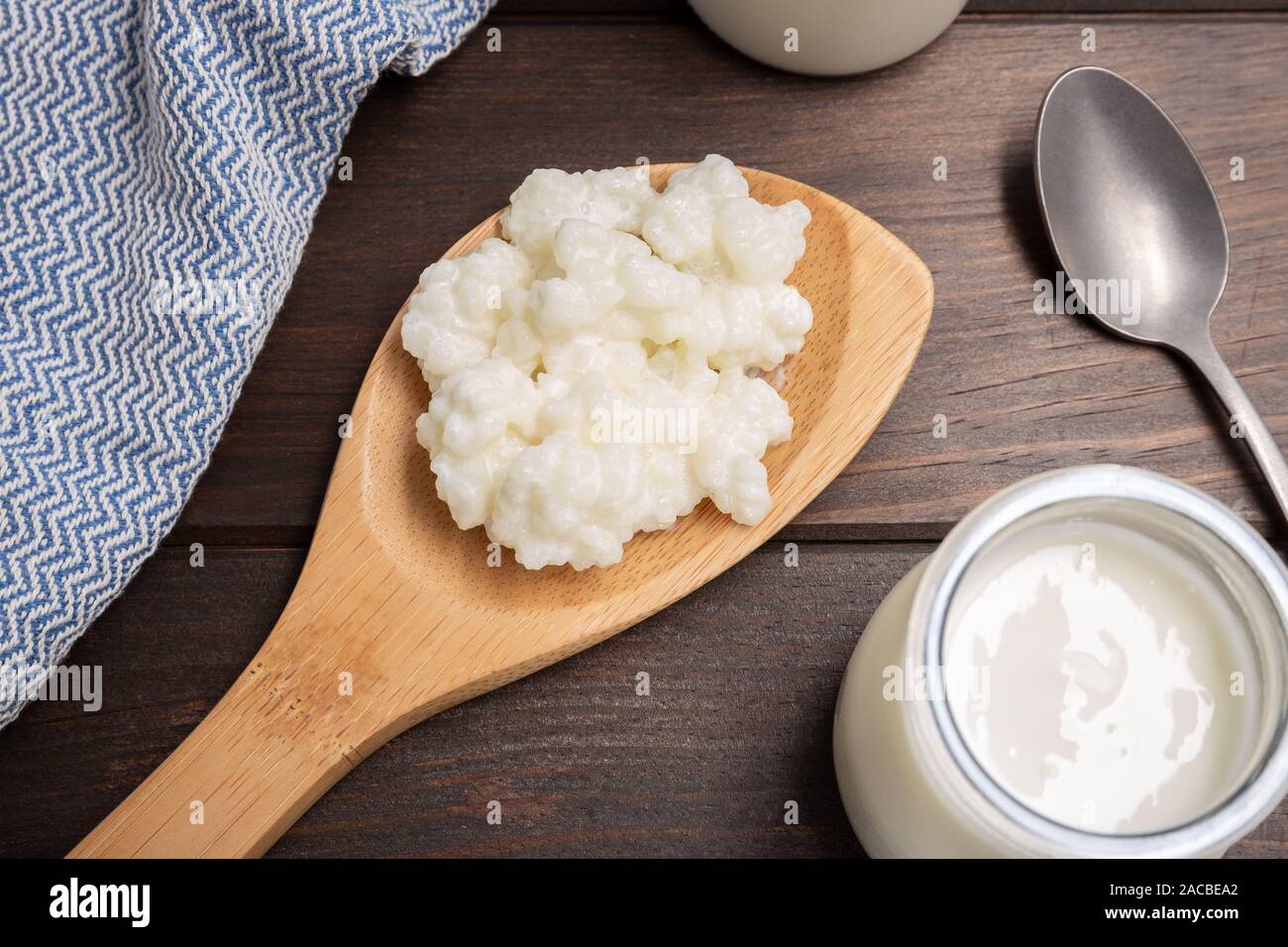 Milch kefir Körner in Löffel auf Holztisch. Hefe bakterielle Fermentation starter Stockfoto