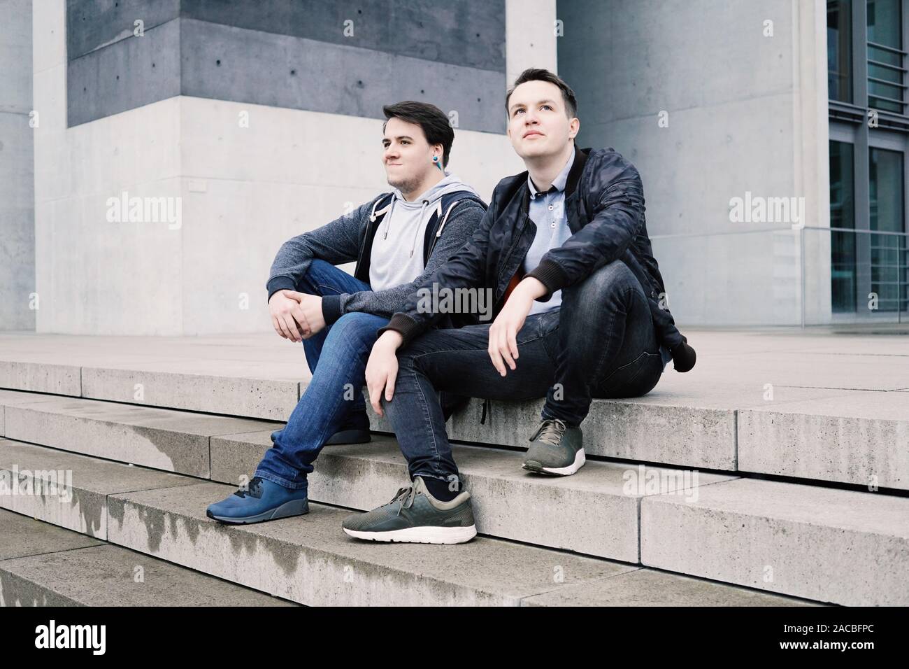 Zwei männliche Teenager Freunde oder Brüder zwei männliche Teenager Freunde sitzen auf konkrete Schritte oder Treppenhaus außerhalb - städtische Jugend lifestyle Stockfoto